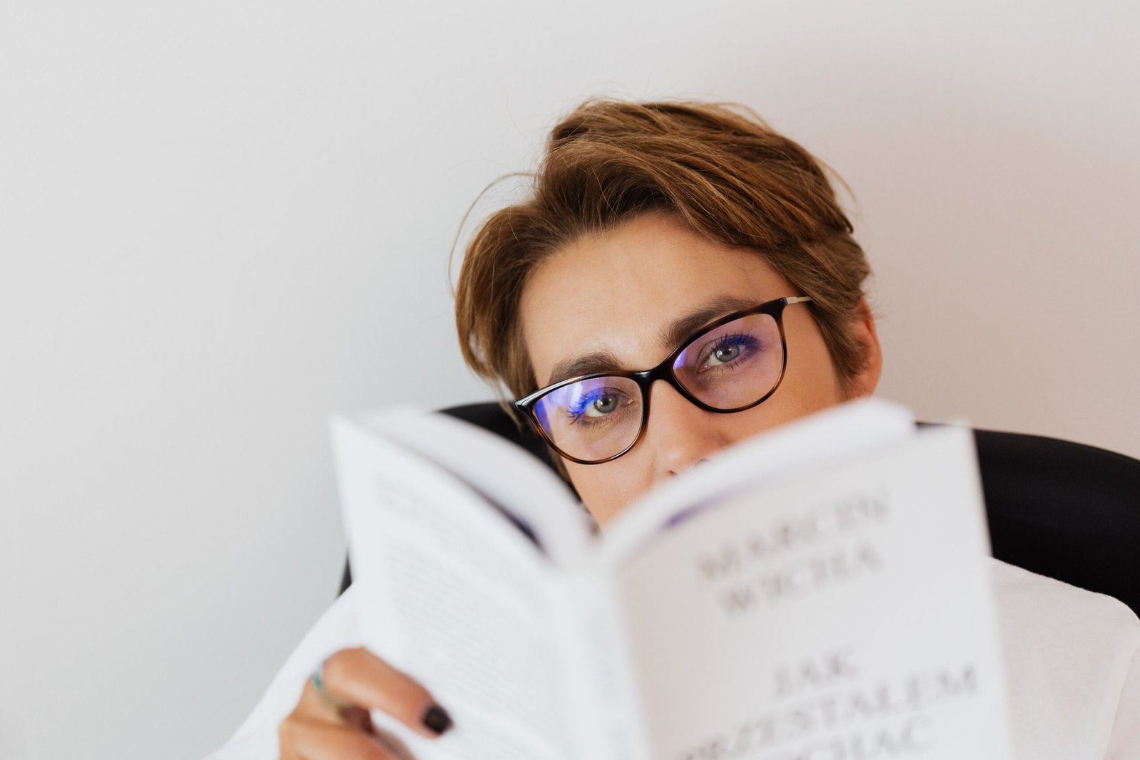 Mujer joven con anteojos leyendo en casa