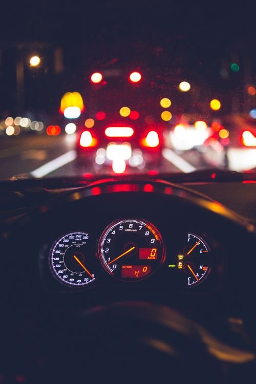 Vista desde el interior de un auto conduciendo de noche por calles iluminadas de la ciudad