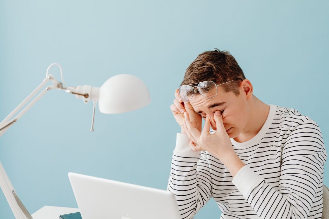 Persona cansada frente a una laptop con lámpara de escritorio durante el trabajo nocturno