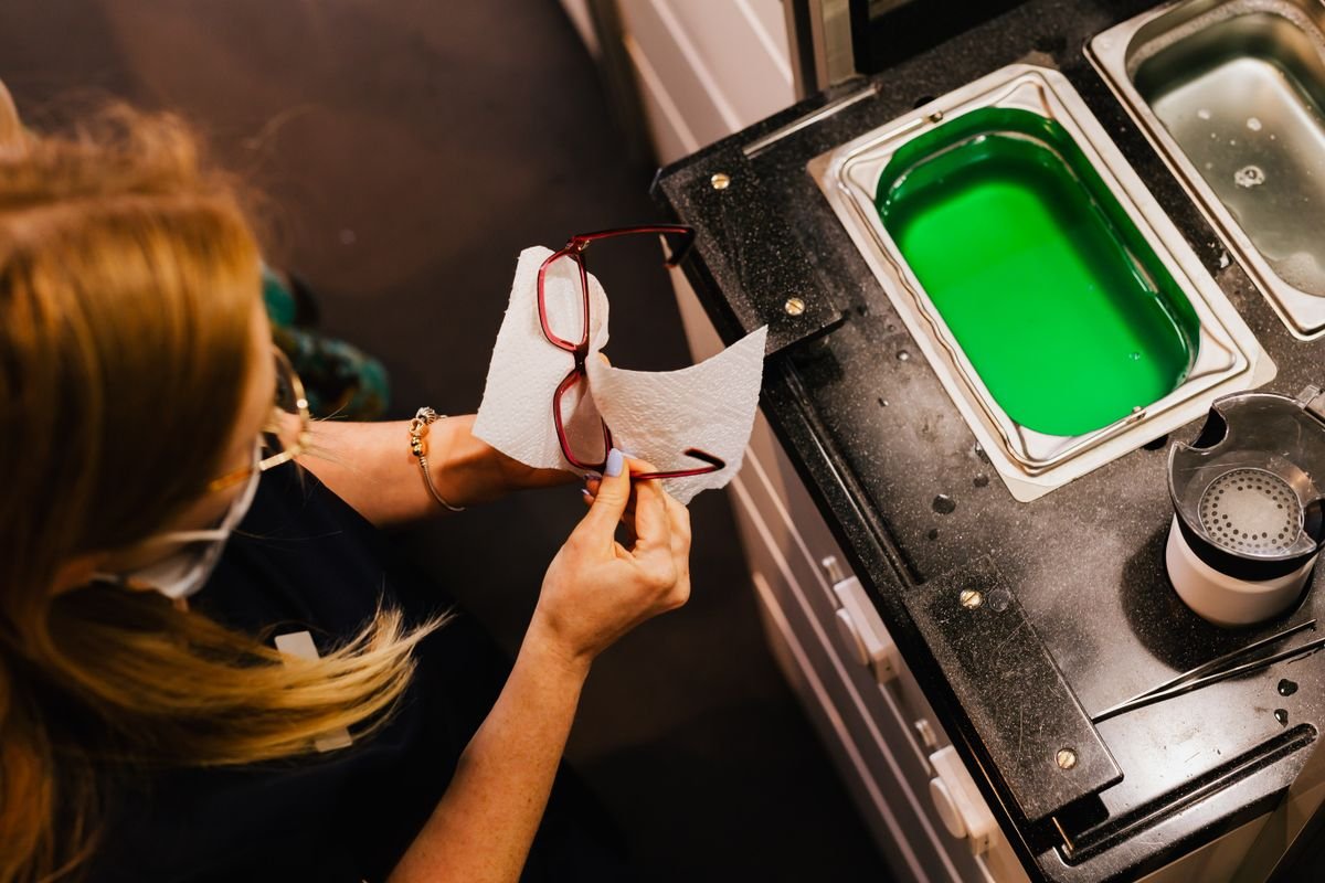 Óptica limpiando unos lentes con la técnica correcta