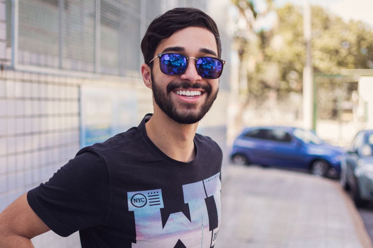 Hombre sonriente con lentes de sol modernos al aire libre