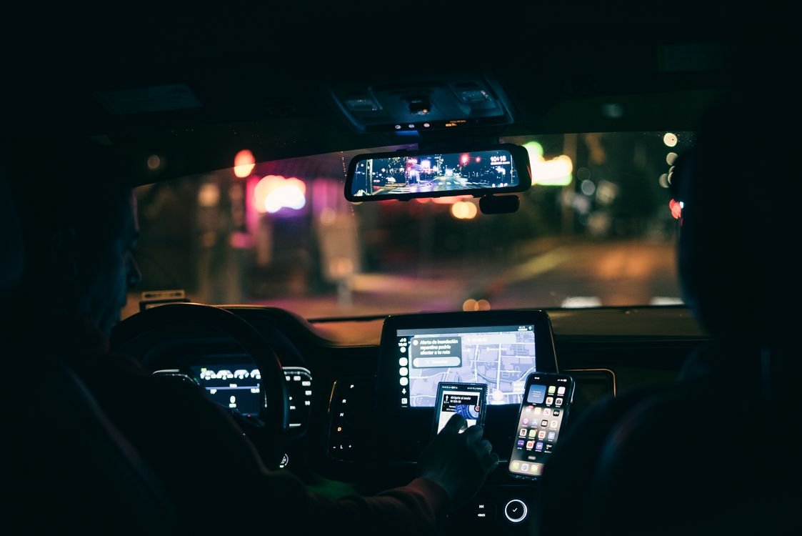 Hombre conduciendo un auto de noche con las luces de la carretera visibles