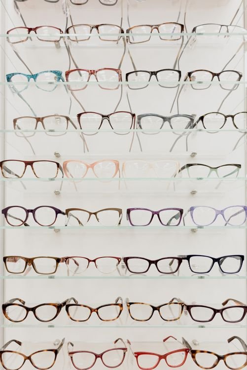 Variedad de monturas de lentes de acetato y metal exhibidas en estantes de una óptica